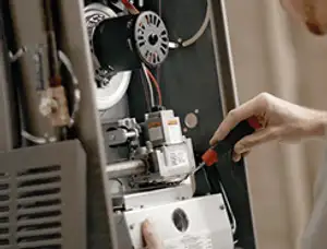 Furnace repair technician inspecting internal components and wiring in Austin, TX