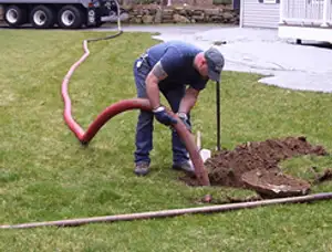 Septic pumping technician servicing a residential septic tank with a vacuum hose in Austin, TX