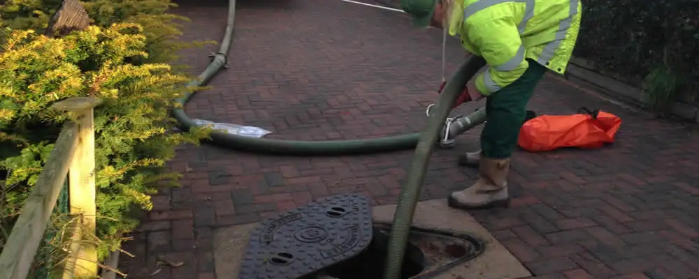 Septic tank cleaning technician servicing a septic tank with a vacuum hose in Austin, TX