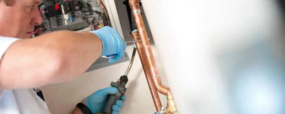 Water heater repair technician testing copper pipe connections and controls in Austin, TX